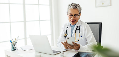 Doctor in a lab coat using a smartphone in her office