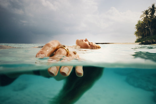 Woman relaxing in tropical ocean water with serene island in the background