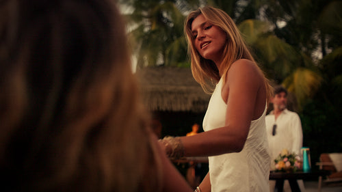 Happy mother and daughter dancing together at an outdoor evening party in a tropical resort