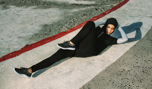 Sportswoman in hijab doing bicycle crunch workout