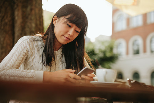 Young woman with a coffee using mobile phone