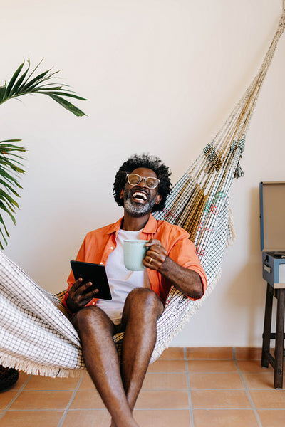 Relaxed man enjoying coffee and technology in a hammock
