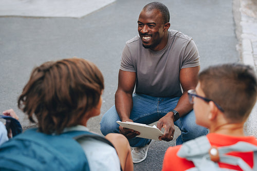 Happy teacher having a pep talk with his students outside