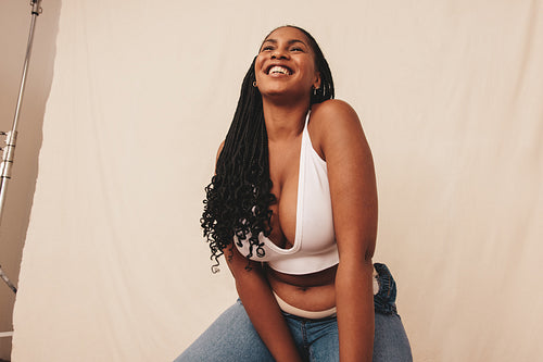 Carefree young woman smiling while sitting on a chair in a studio