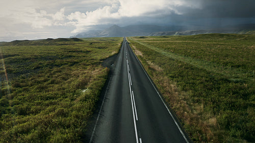 Asphalt road passes through the lush green field