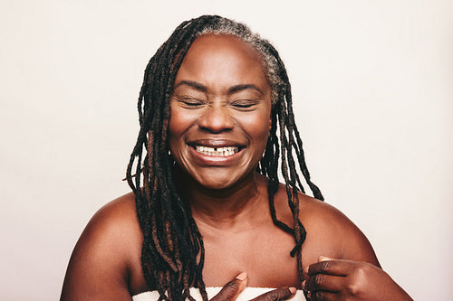 Cheerful mature woman laughing cheerfully in a bath towel