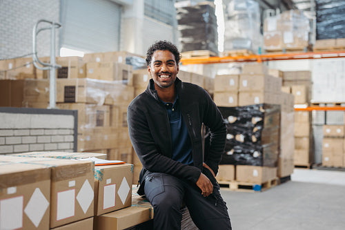 Happy logistics worker smiling at the camera in a warehouse