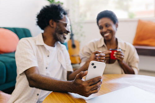 Couple enjoying quality time at home, smiling and using a smartphone