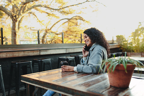 Woman sitting at a coffee shop talking over phone