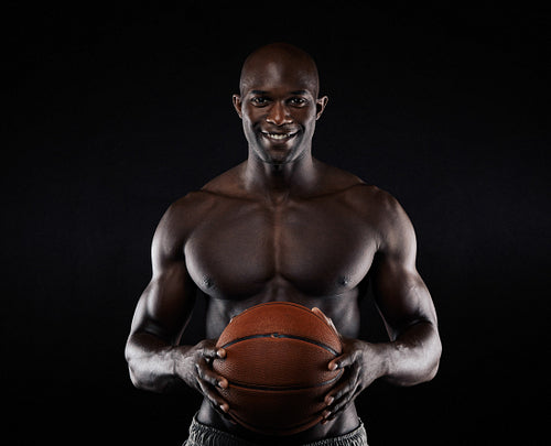 Shirtless basketball player looking at camera smiling.