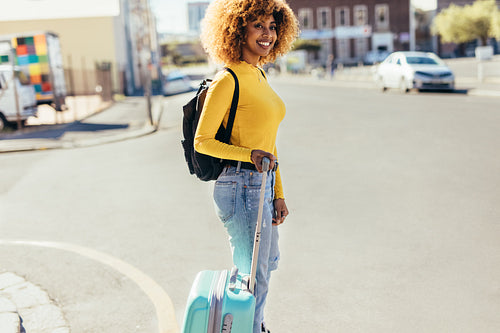 Tourist woman crossing the street holding luggage