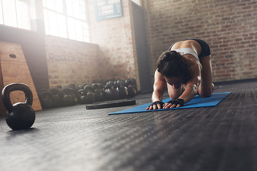 Woman on exercise mat doing stretches at gym