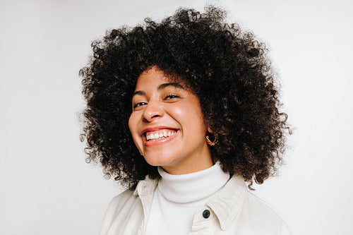 Woman with curly hair smiling at the camera cheerfully