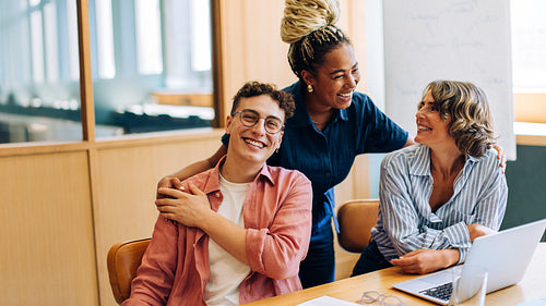 Three smiling adults enjoying a moment of laughter in a cozy office setting