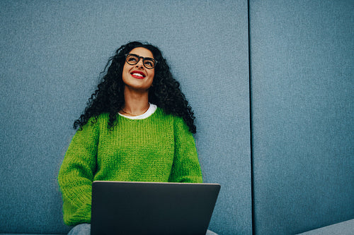 Smiling, the woman uses a laptop at home for casual online work