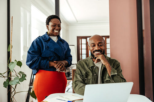 Manager and colleague reviewing a presentation with a laptop in a stylish modern office