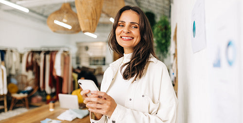 Portrait of a fashion designer using a phone in a clothing boutique
