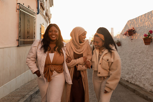 Three happy friends laughing together outdoors