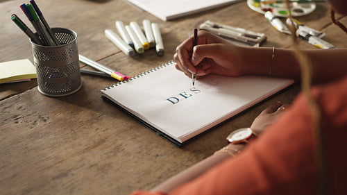 Imaginative young woman drawing the word "DESIGN" on a notepad