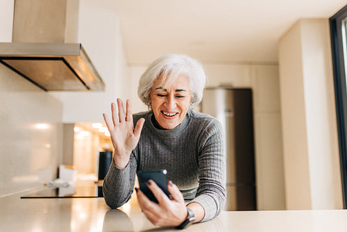 Cheerful elderly woman waving her hand during a video call