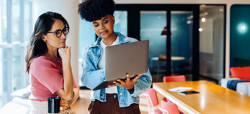 Guiding the workflow: Young woman presents updates to a teammate