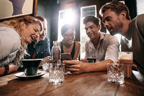 Friends looking at mobile phone while sitting in cafe
