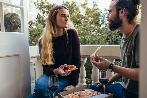 Couple eating a pizza sitting at home