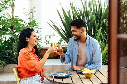 Couple enjoying a cheerful outdoor meal together with drinks and laughter