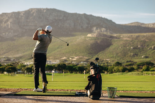 Man practicing his golf swing surrounded by beautiful outdoor mountain scenery