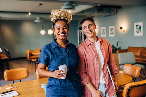 Two individuals smiling confidently together in a welcoming meeting room environment