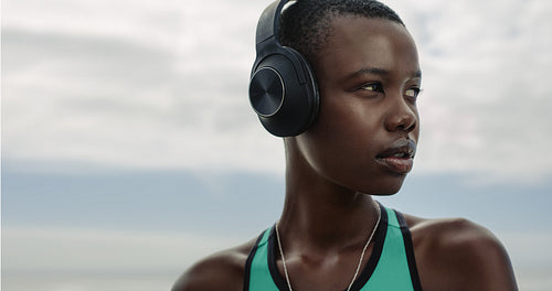 Sporty woman with headphones standing outdoors