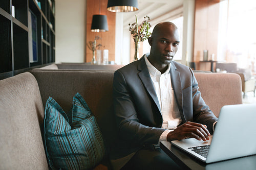 African businessman working on laptop in coffee shop