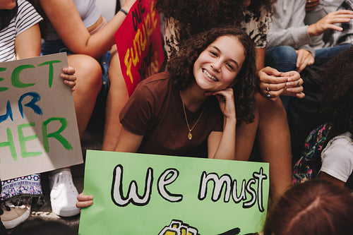 Cheerful teenage girl sitting with a group of climate activists