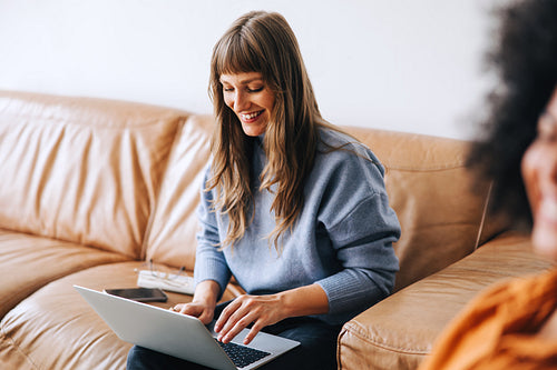 Cheerful young businesswoman using a laptop in a lobby
