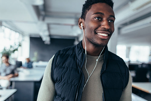 Happy african man listening music in office