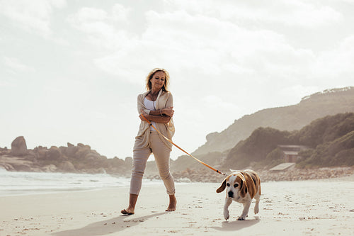 Mature woman walking her dog on the beach