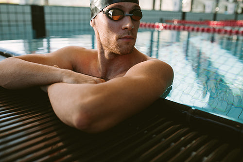 Pro male swimmer relaxing at pool edge