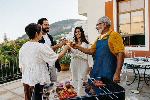 Family toasting drinks at a Brazilian churrasco on a sunny patio