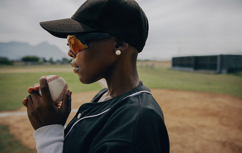 Determined baseball pitcher holding ball in uniform at an outdoor field ready for a game