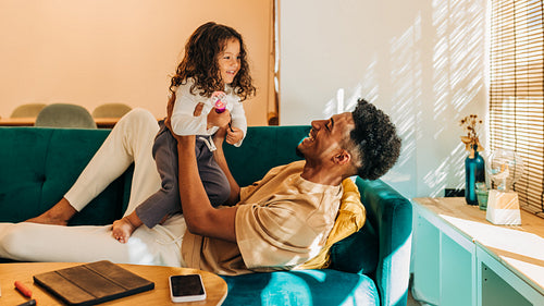 Happy single dad lifting and playing with his daughter at home
