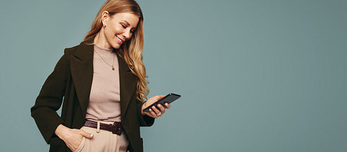 Smiling woman reading a texte message in a studio