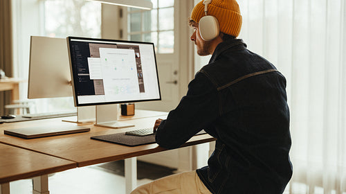 Focused professional working at computer with headphones