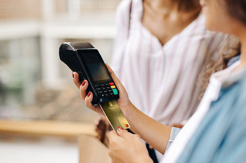 Shop owner swiping a credit card on a card reader while serving a customer