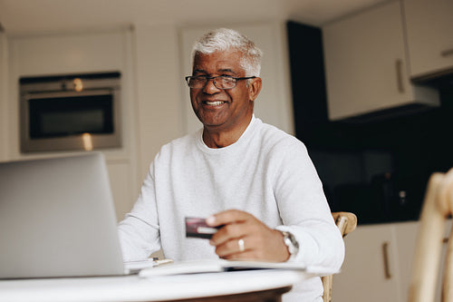 Happy senior man shopping online at home