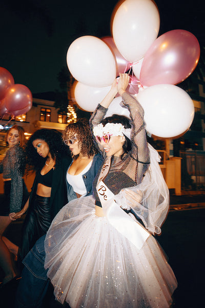 Group of friends celebrating a bachelorette party with balloons at night