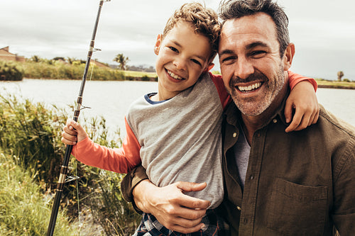Close up of father and son fishing near a lake