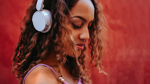Calm music fills a woman wearing headphones outdoors in profile