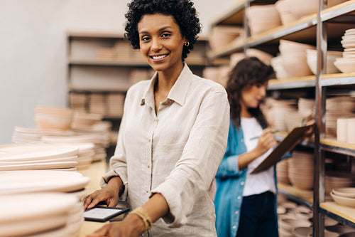 Cheerful female ceramist smiling at the camera in her shop