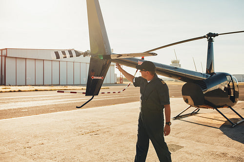 Pilot checking helicopter tail during preflight check 