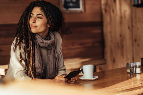 Woman sitting in a cafe holding her mobile phone